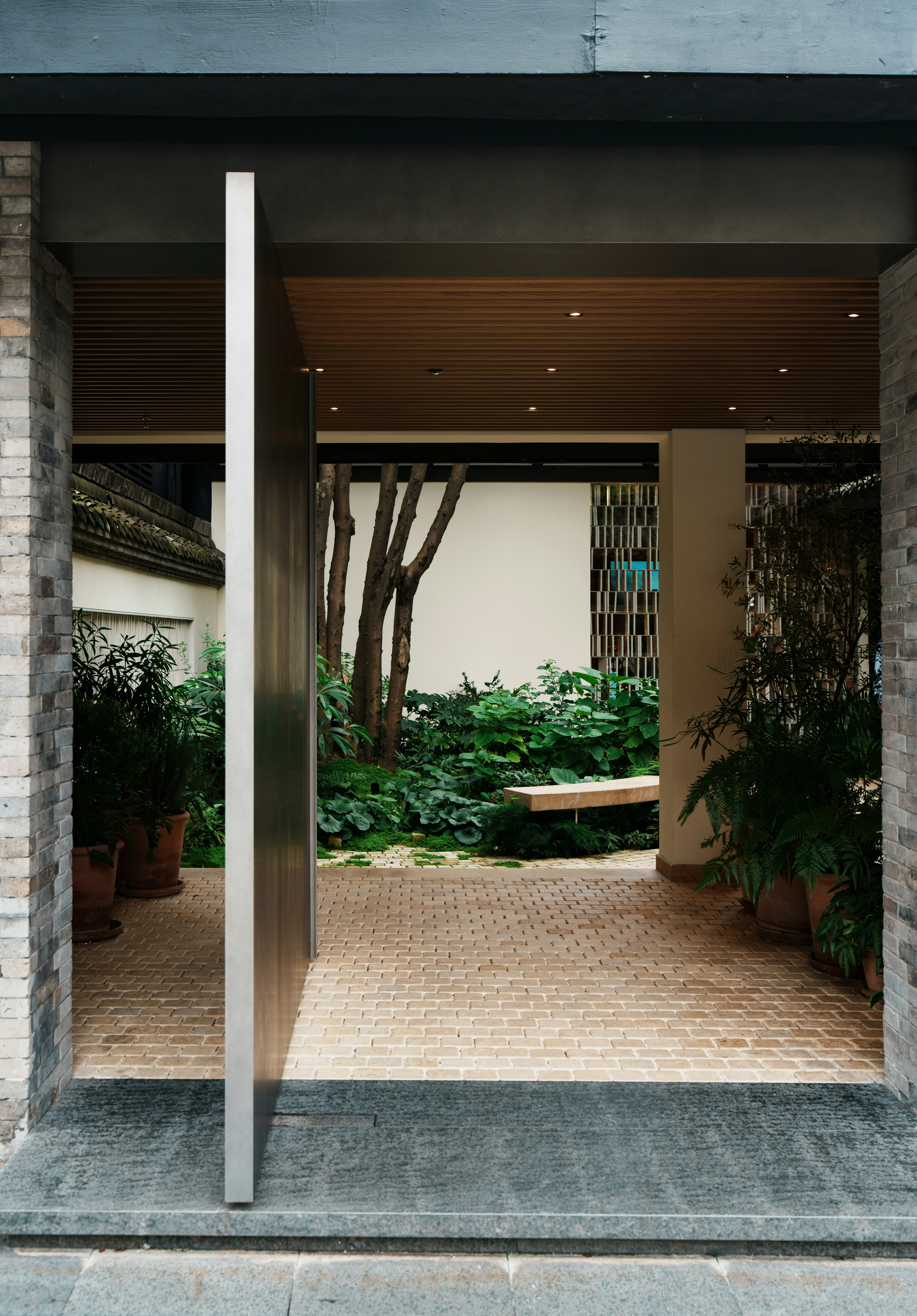 Projet cœur urbain — porche bois ouvrant sur un patio de briques végétalisé